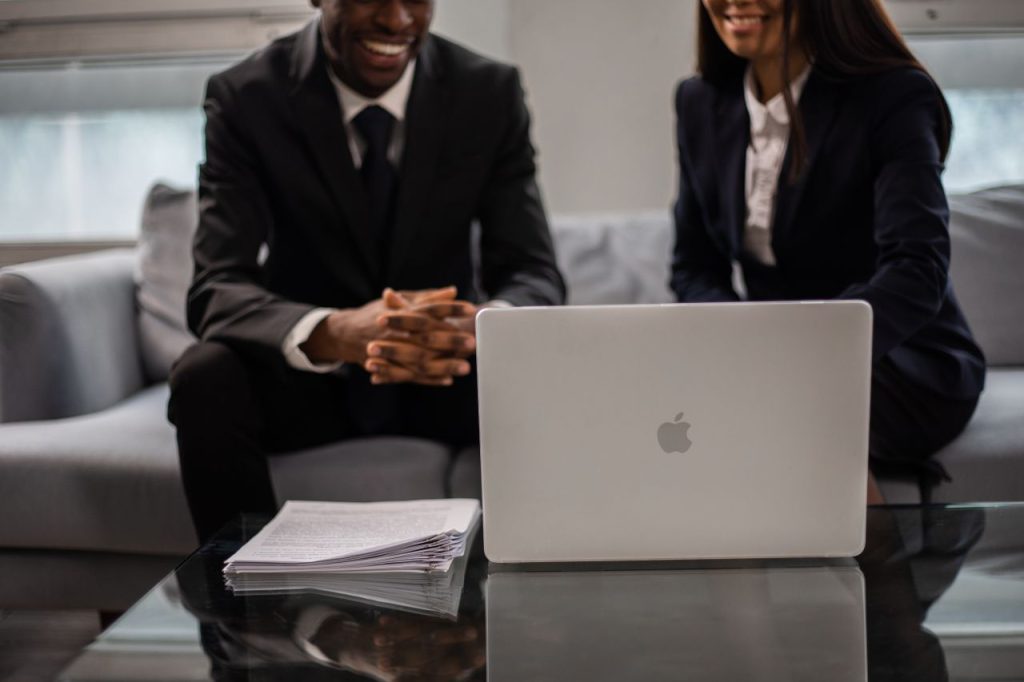 pexels photo 6077775 Professional two-person team having a discussion in an office setting with laptop.