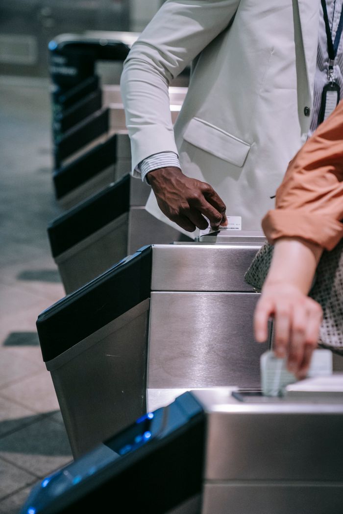 Services Close-up of commuters passing through turnstiles at a subway station entrance.